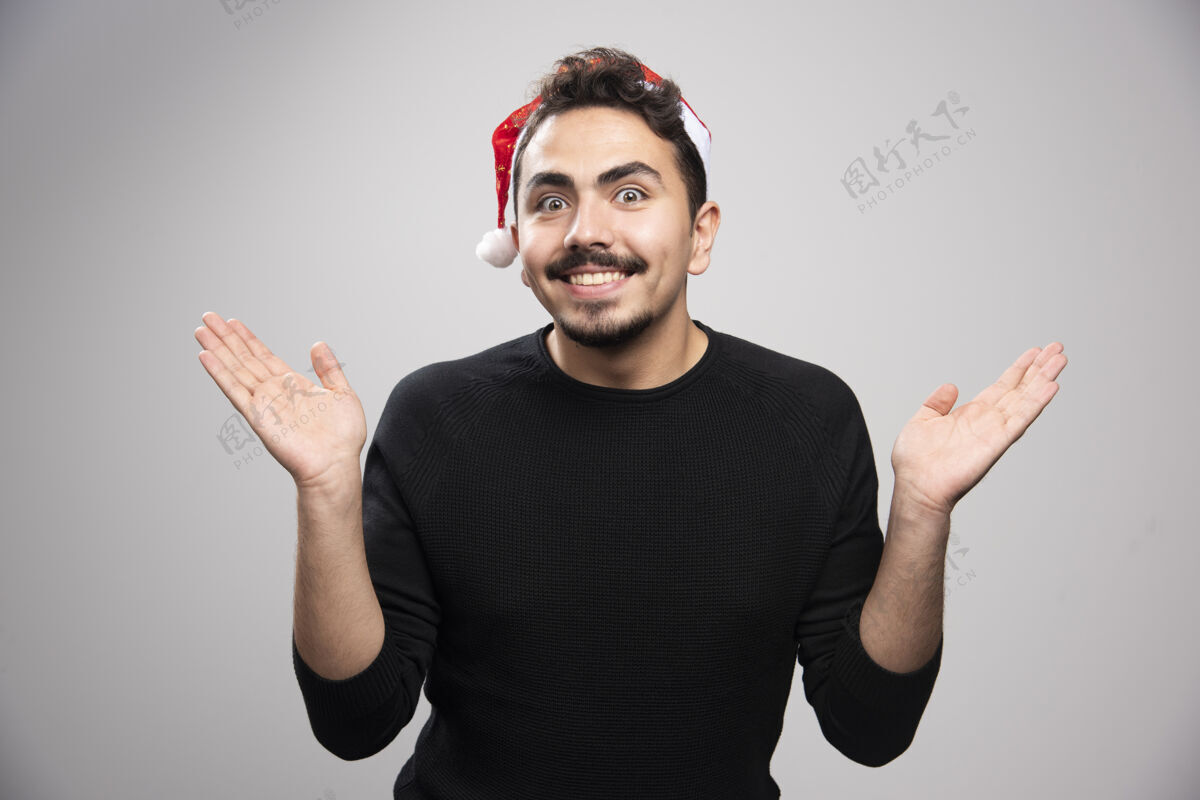 人戴圣诞老人帽子的年轻人手里拿着看不见的东西开放成人年轻