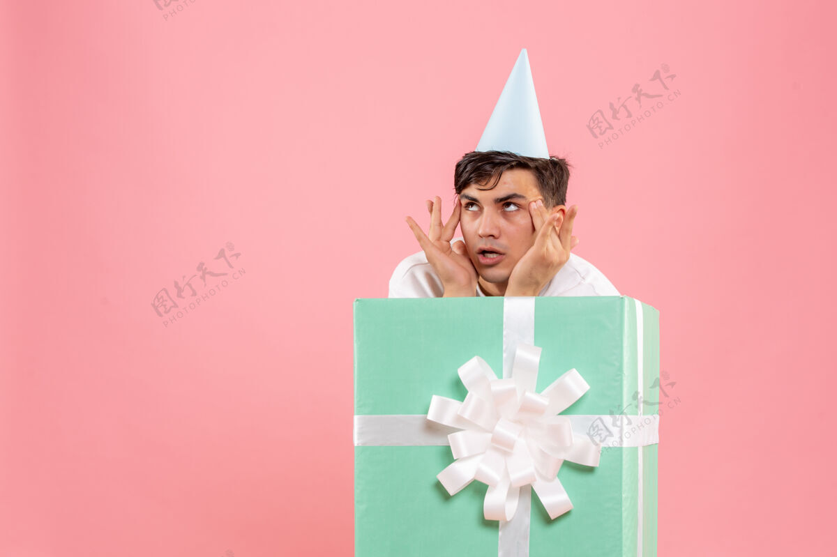盒子年轻人躲在粉红色墙上思考的眼前粉色圣诞年轻男性