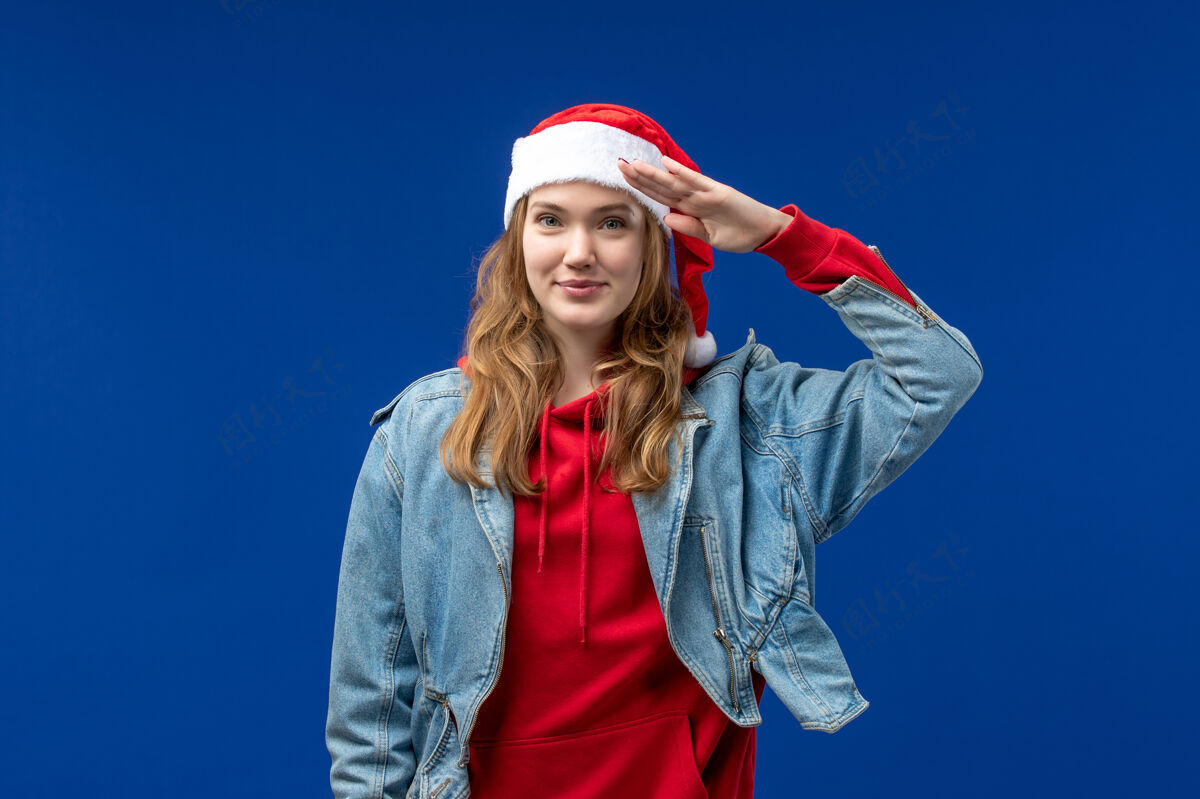 微笑前视图年轻女性 蓝色背景 红色圣诞帽 情感圣诞色一个年轻女性开朗