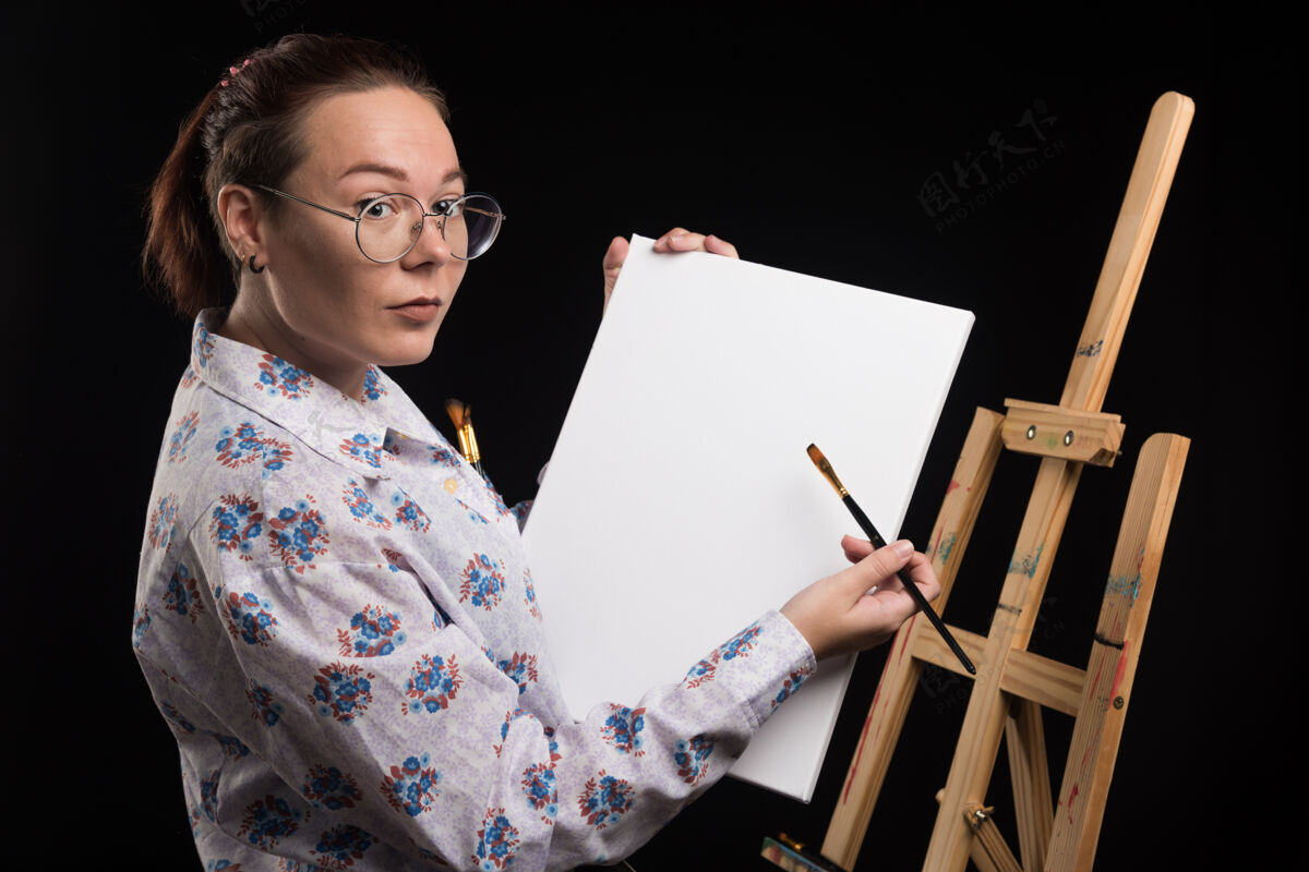 艺术女艺术家在黑色背景上用画笔展示她的画布艺术女人画布