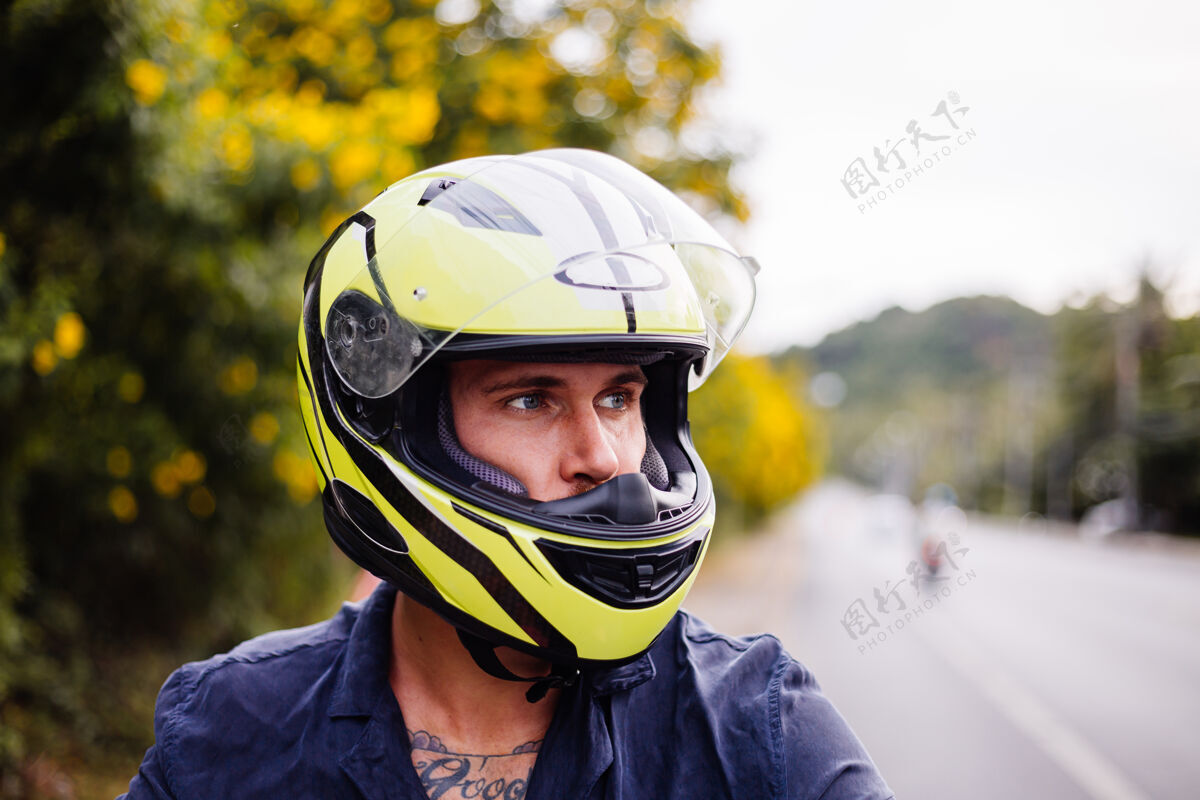 车辆在泰国繁忙的公路边骑摩托车的戴着黄色头盔的男摩托车手的画像时尚街道出租