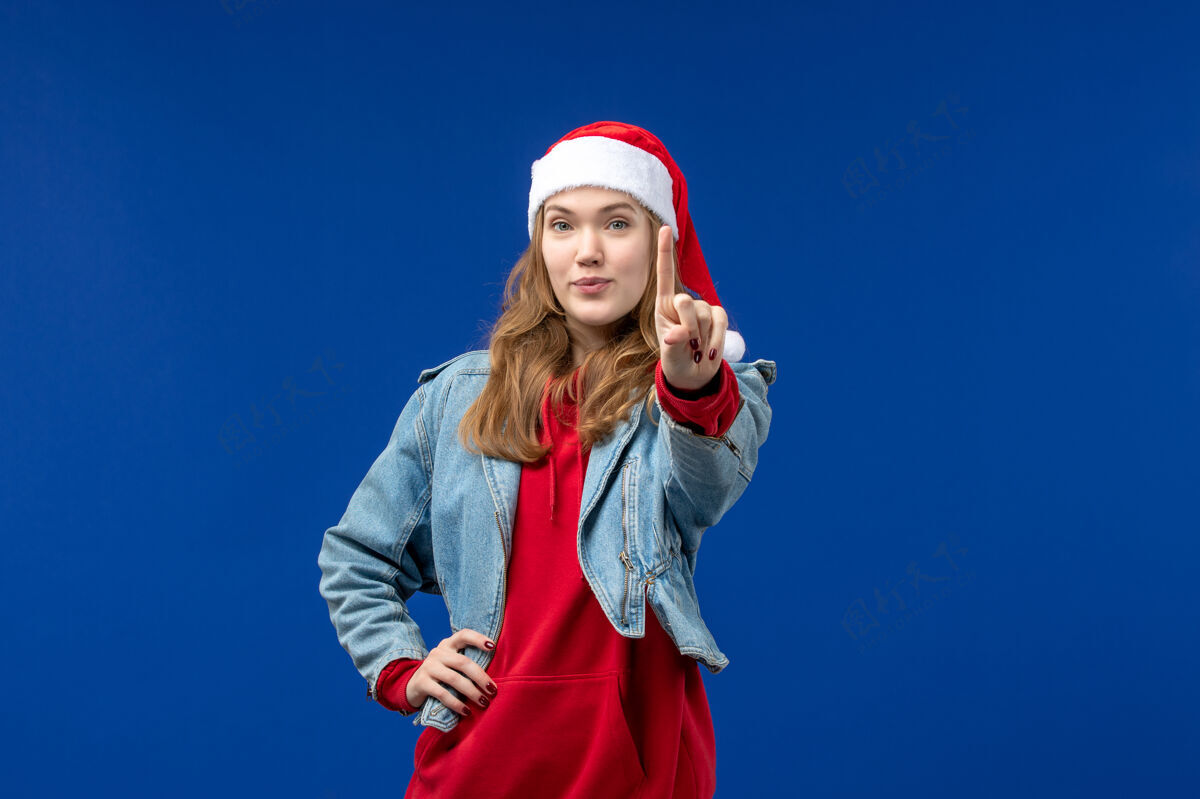 蓝色前视图年轻女性 蓝色背景 红色圣诞帽 圣诞情感色彩观点情感可爱