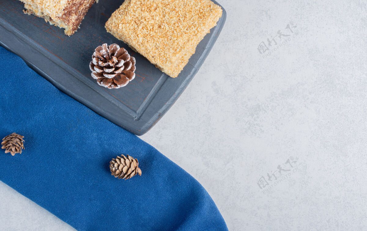 圆锥体在海军蓝板上的蛋糕片 大理石表面有松果糖蛋糕装饰的