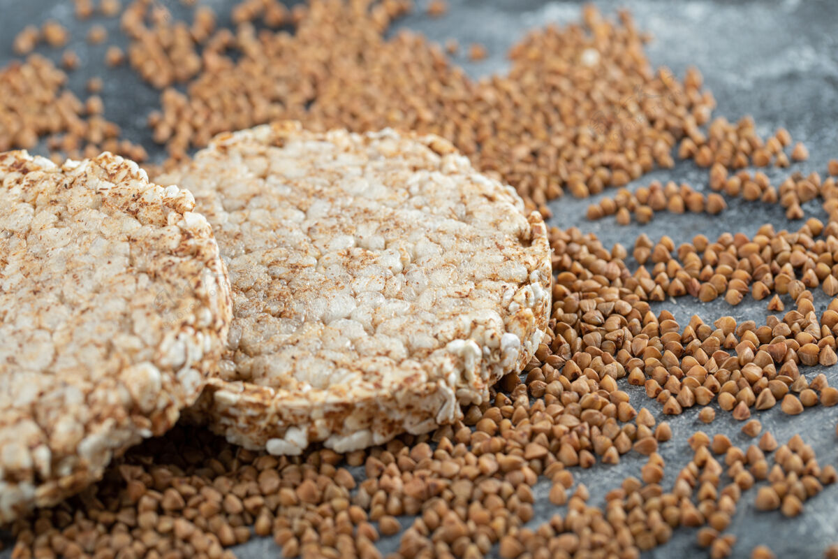 谷物两个脆面包和生荞麦放在大理石表面天然荞麦生的