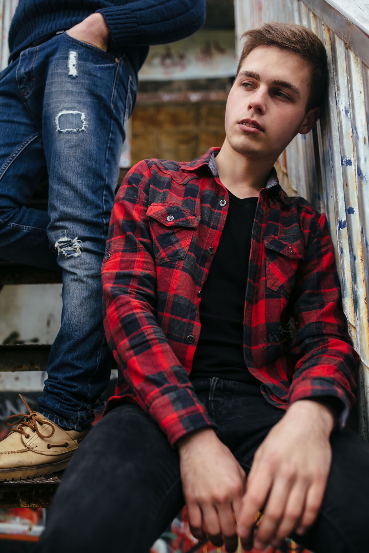 外观两个年轻人站在楼梯上一栋废弃的大楼里牛仔膝盖人