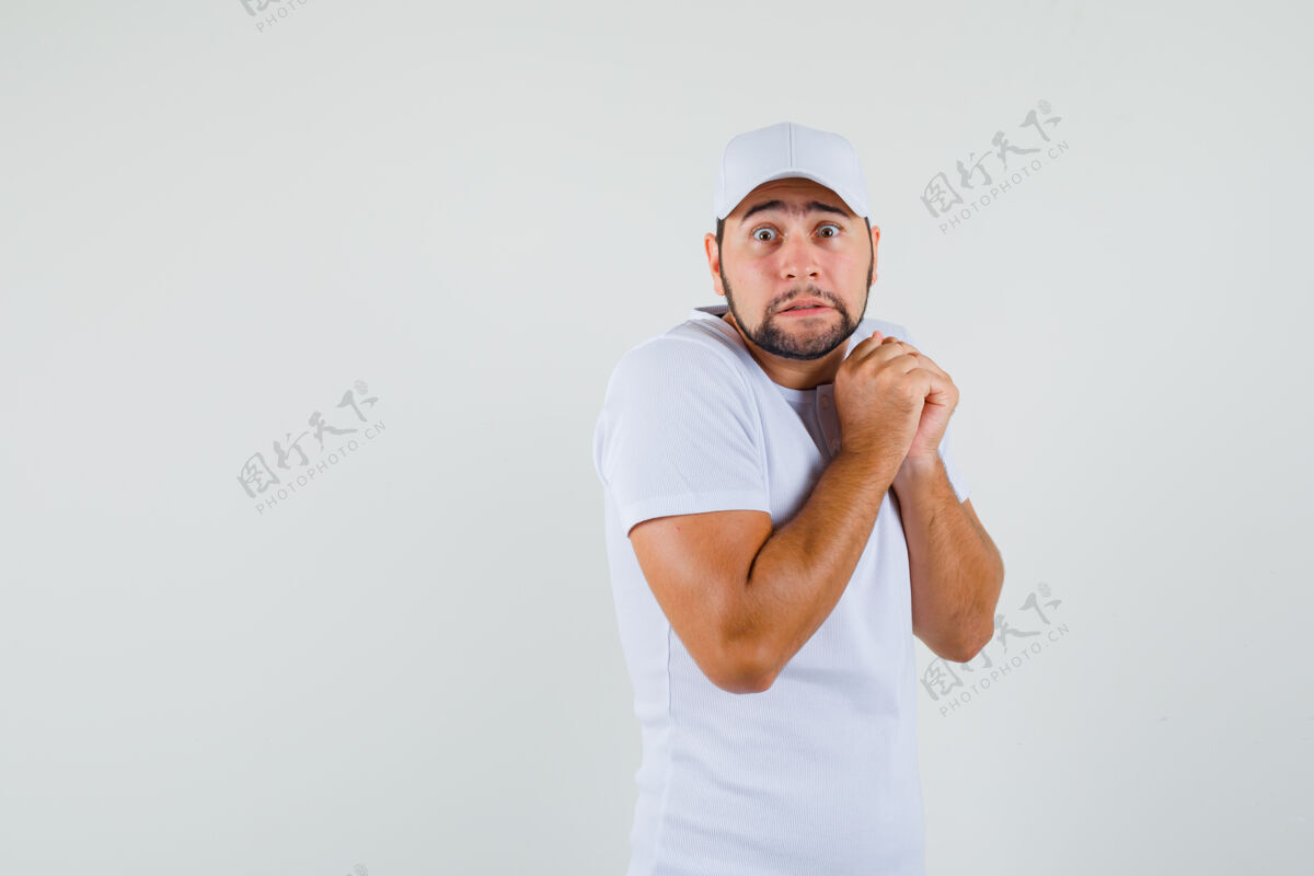 男性一个穿着白色t恤的年轻人把拳头放在胸前 看起来很不舒服现代休闲帅哥