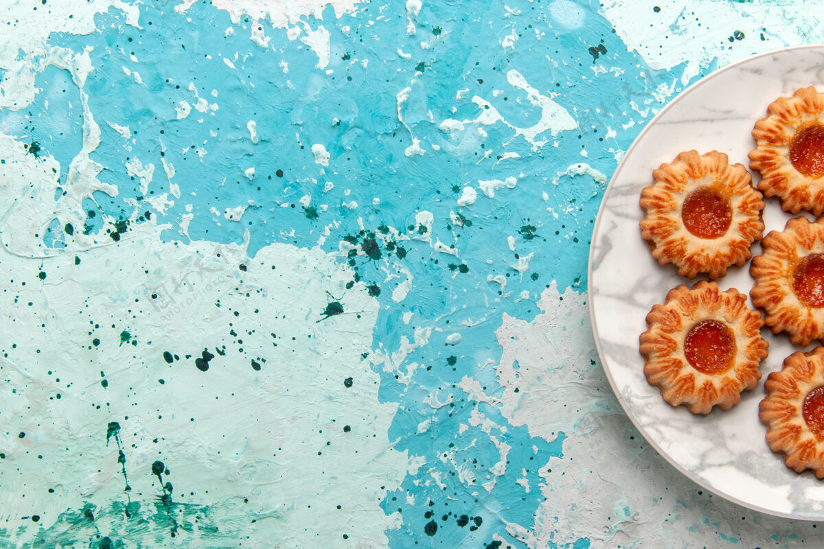 饼干俯瞰美味饼干圆形果酱形成的浅蓝色桌子上的盘子饼干糖甜饼干面团蛋糕烘烤里面浅蓝色蛋糕