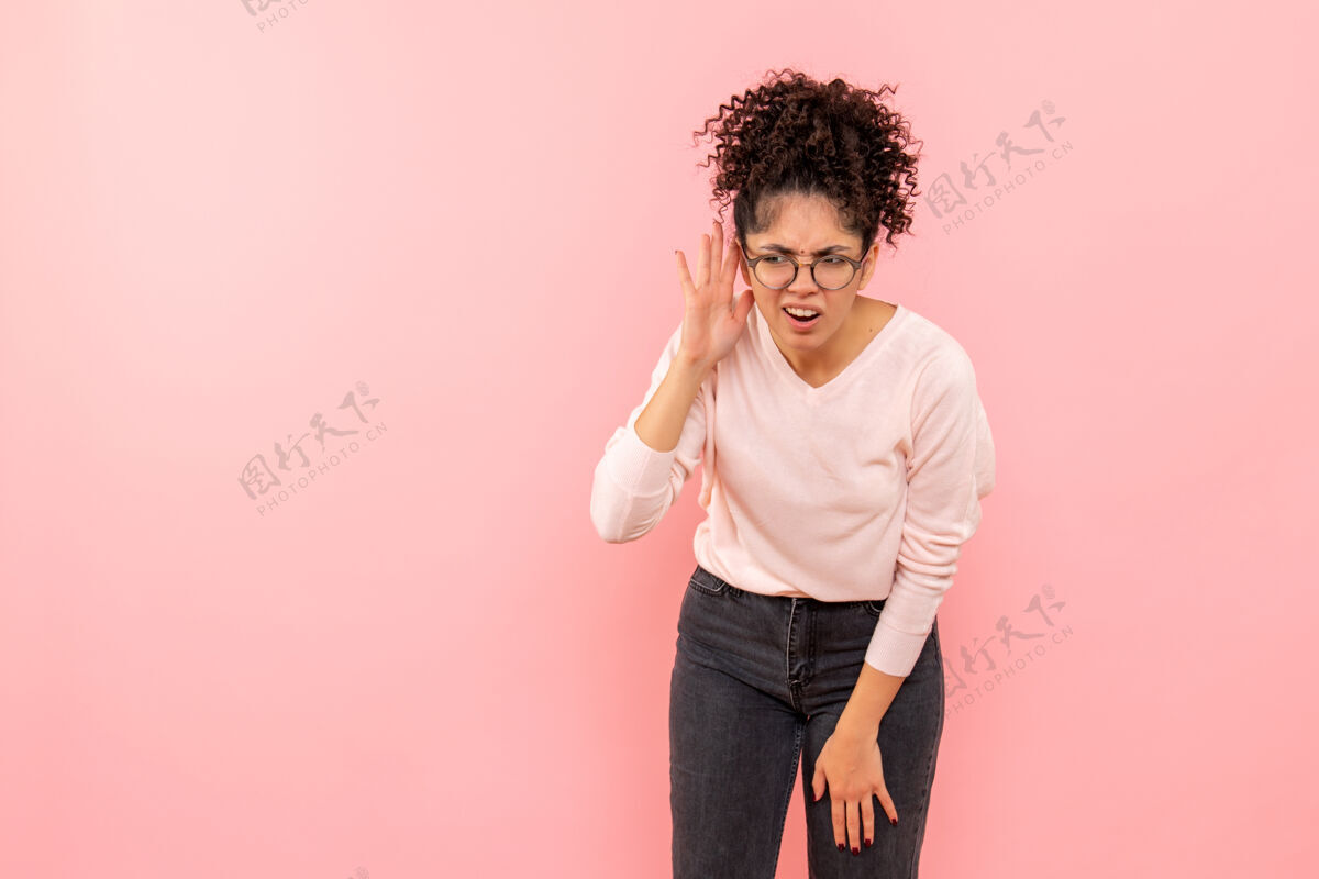 美丽年轻女子在粉色墙壁上聆听的正视图倾听模特快乐