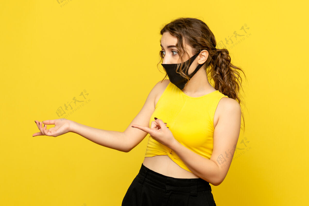 肖像黄色墙上戴着面具的年轻女子的正视图人物女士病毒