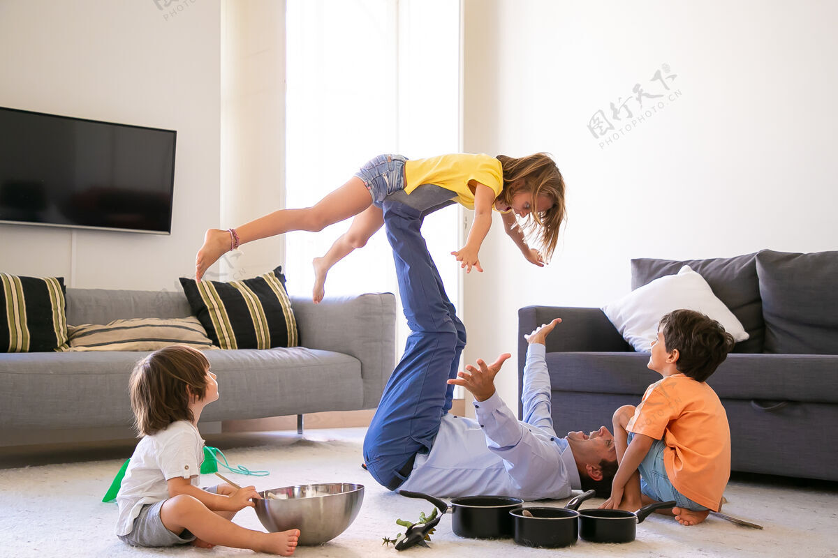 地毯快乐的父亲抱着女儿双腿躺在地毯上快乐的白人孩子和爸爸在客厅里玩耍两个可爱的男孩坐在地板上童年 节日和游戏活动的概念活动爸爸孩子