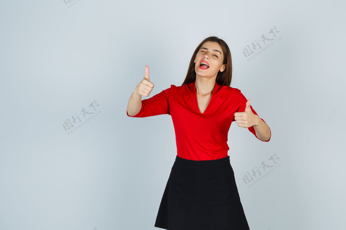快乐穿红衬衫 黑裙子的年轻女子竖起大拇指 看上去很高兴衬衫展示人