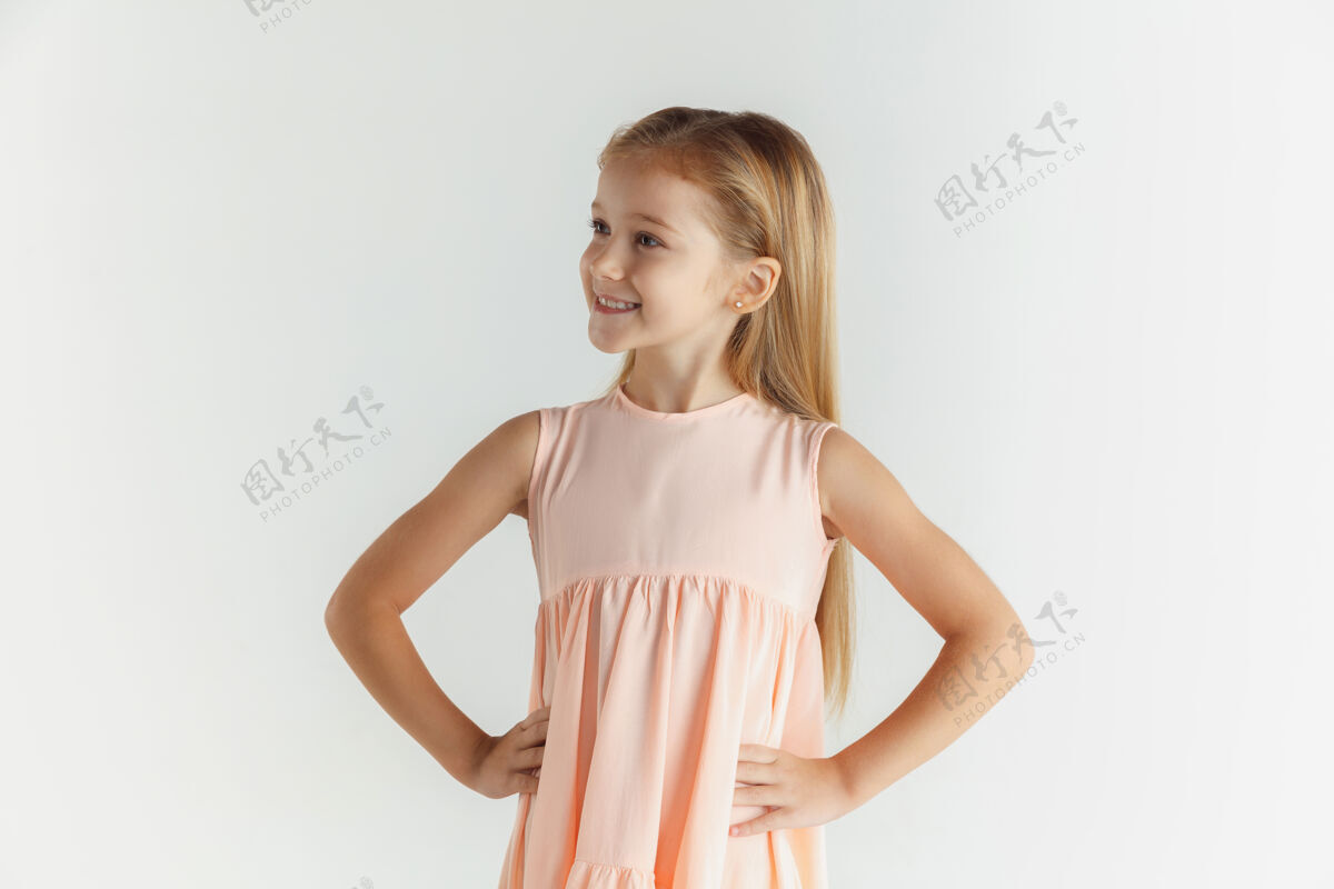 开朗时尚的微笑小女孩在白色工作室里穿着隔离的裙子摆姿势表情童年教育