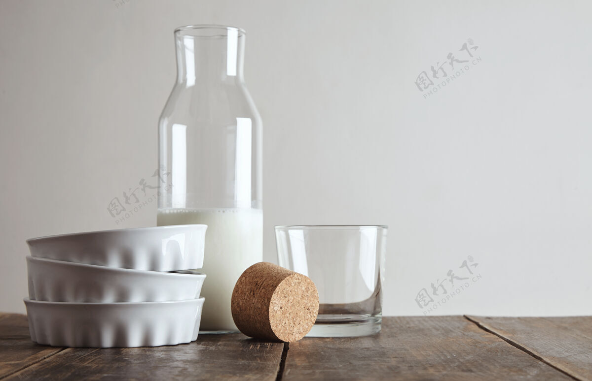 饮食古老的瓶子打开软木塞和牛奶放在老木桌上 靠近威士忌透明玻璃和三个陶瓷盘子 隔离在白色上最小的桌子瓶子