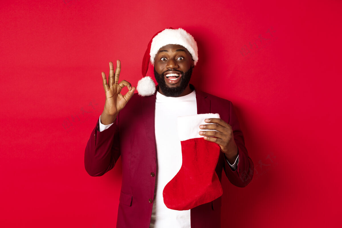 认可惊讶的黑人拿着圣诞袜子里的节日礼物胡须圣诞节模特