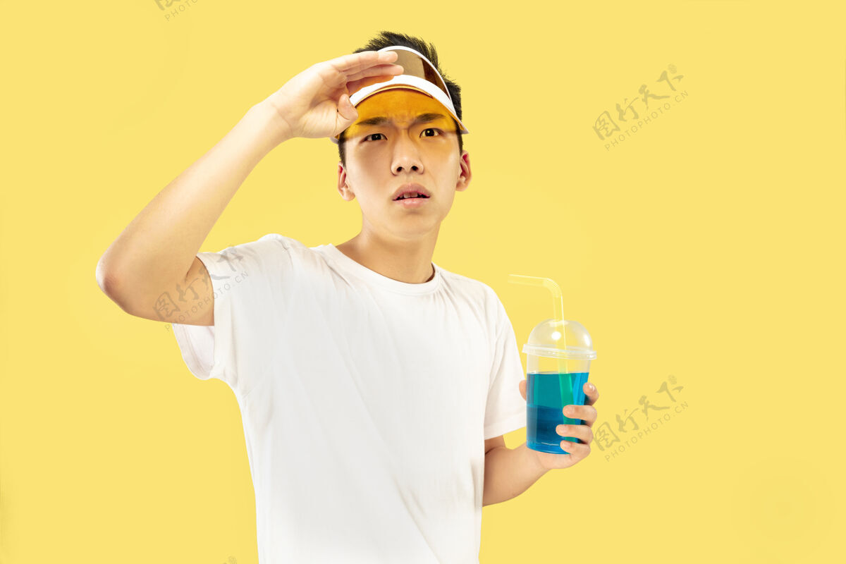 情感韩国年轻人的肖像穿白衬衫 戴黄帽子的男模喝鸡尾酒人类情感的概念 表达 夏天 假期 周末喝酒男海洋