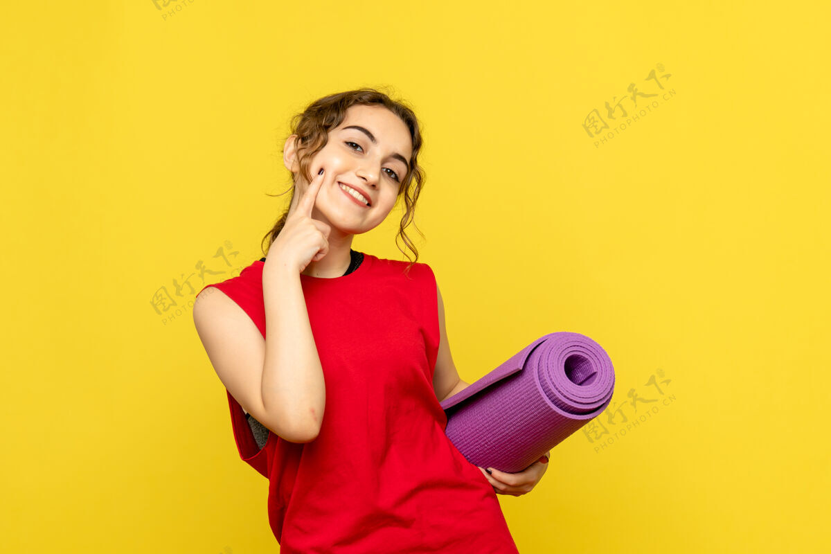 通讯员黄墙上紫色地毯的年轻女子的正视图成人女人瑜伽