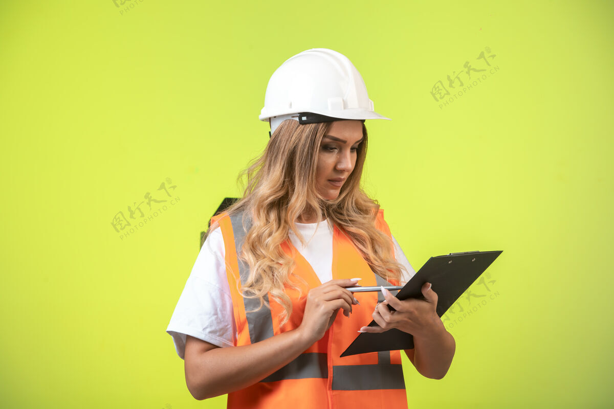 建筑师戴着白色头盔和装备的女工程师拿着检查表看着报告老板工厂工作