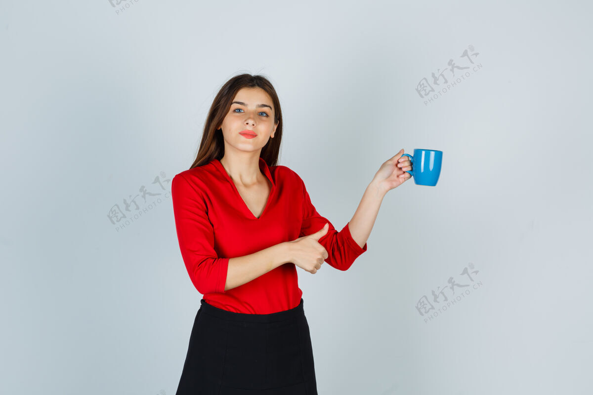 欢快一位穿着红色上衣的年轻女士 一边拿着杯子一边竖起大拇指 看上去很自信人裙子成功