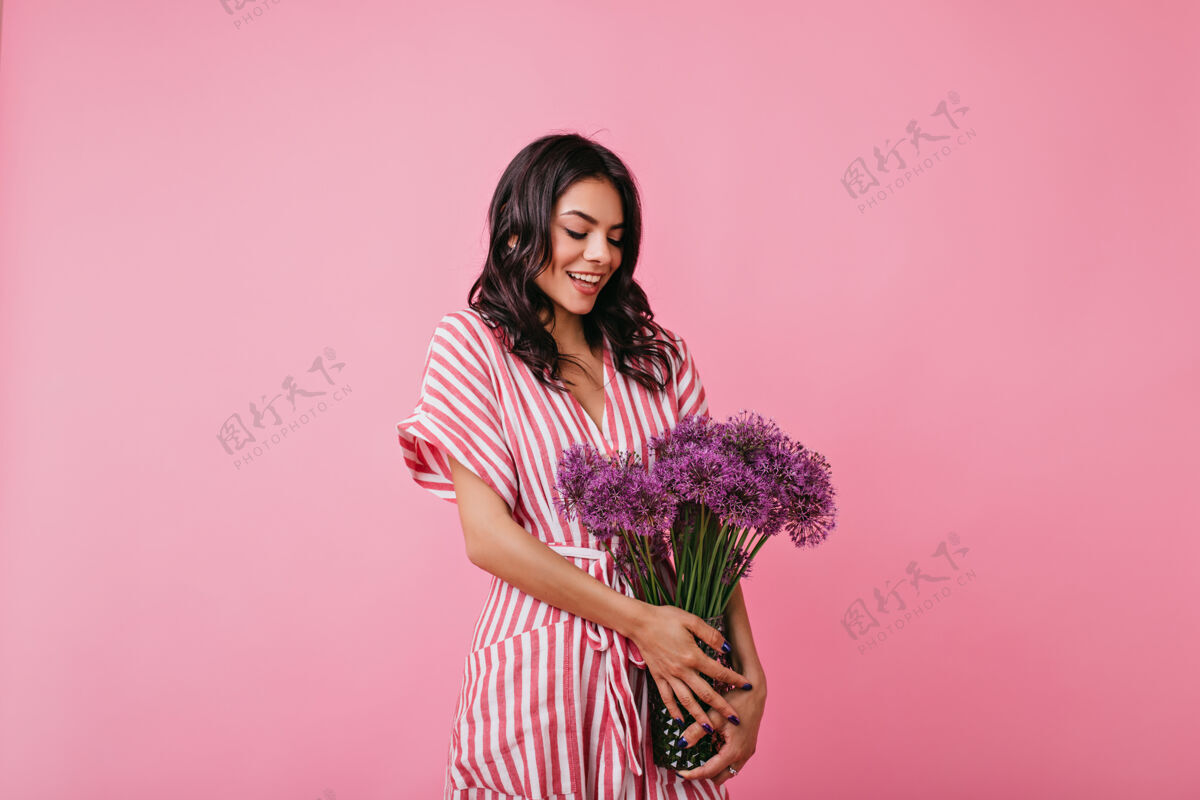 成人迷人的拉丁女人深情地看着一束紫色的野花穿着条纹裙的女孩尴尬地摆姿势美丽快乐情人节