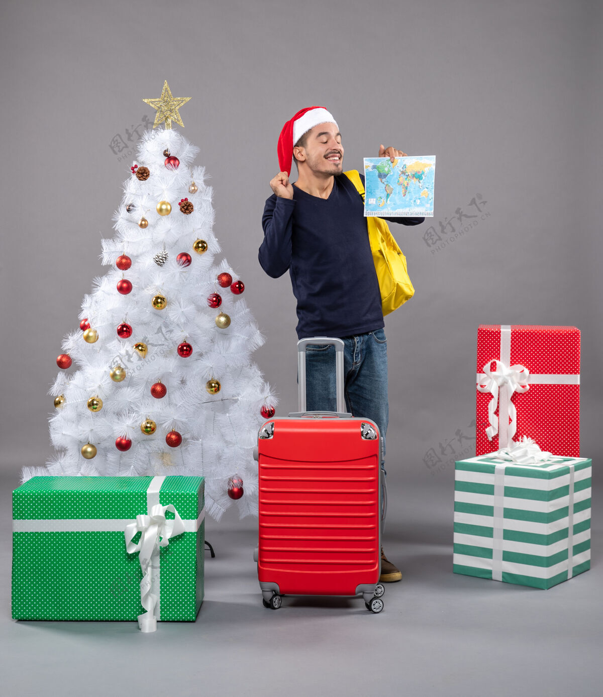 包带着黄色背包的圣诞老人站在灰色的圣诞树旁 欣喜若狂礼物圣诞老人站立