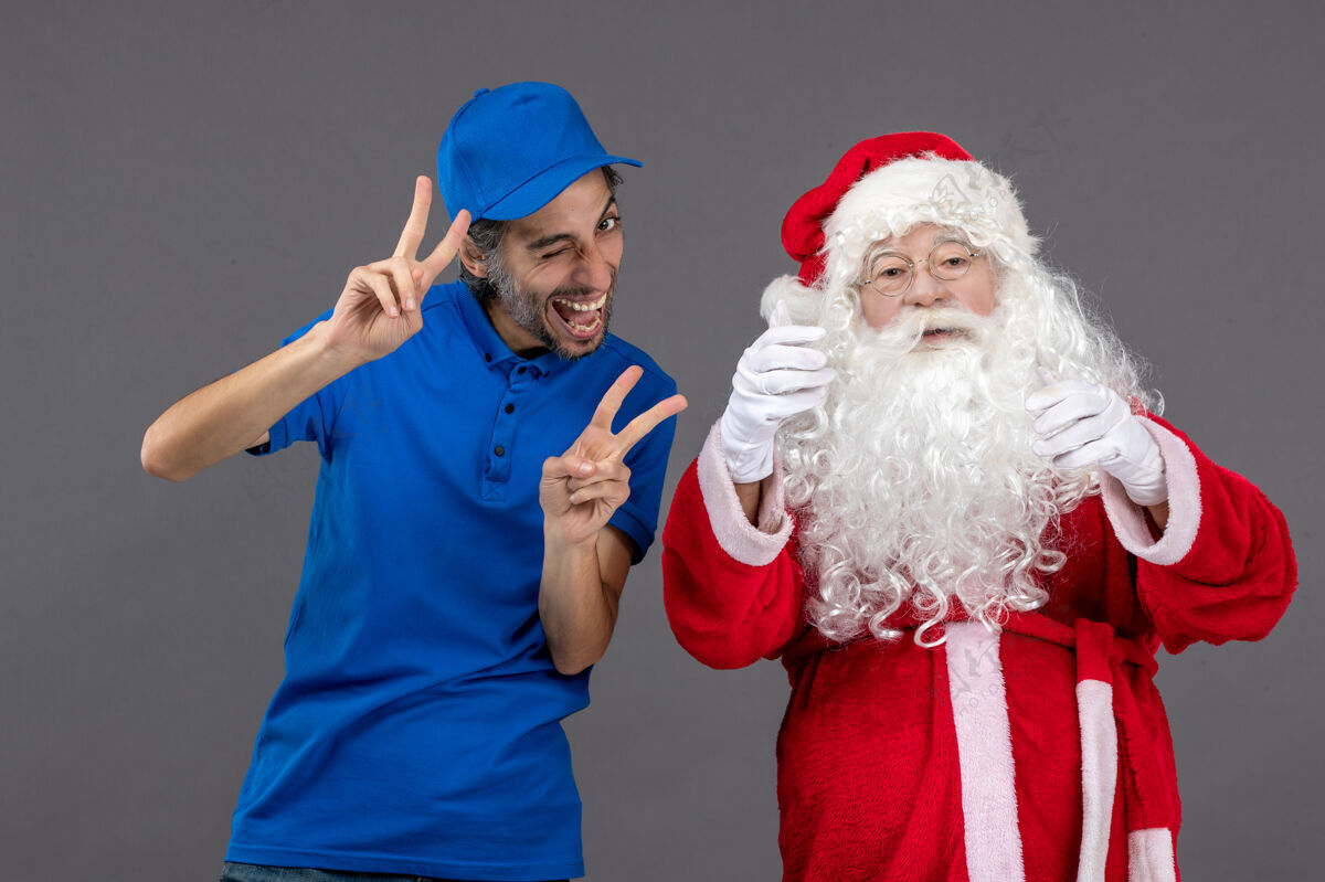 制服灰色墙上的圣诞老人和男信使的正面图信使圣诞圣诞快乐
