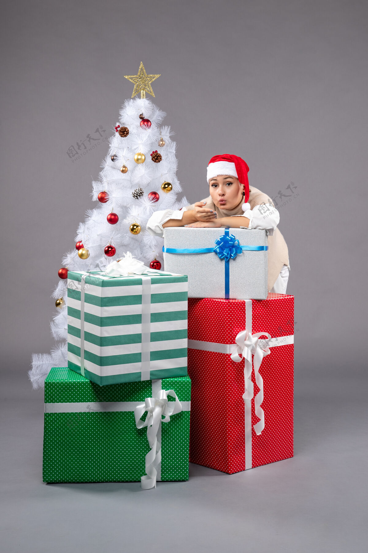 礼物漂亮的女人在灰色的礼物周围桌子圣诞树庆祝