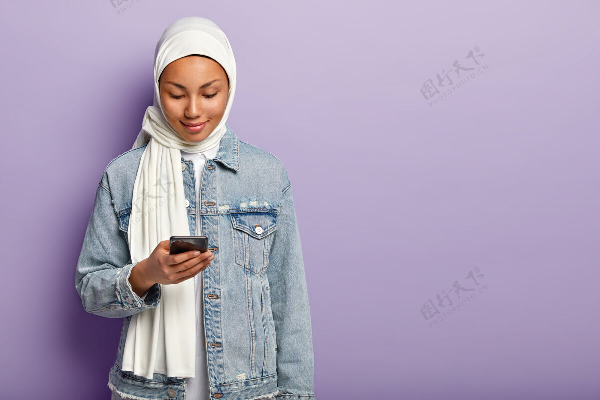 举行照片中的魅力穆斯林女士集中在现代智能手机设备应用程序女性姿势