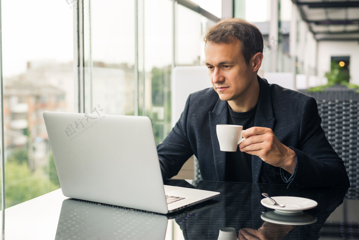 科技商人在咖啡馆喝咖啡 用笔记本电脑工作手机通信自由职业者