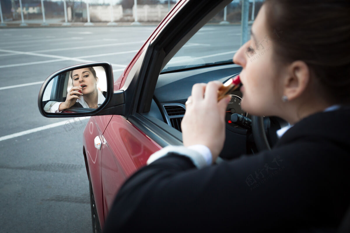 女士漂亮的女商人坐在车里涂口红驾驶嘴唇壁板