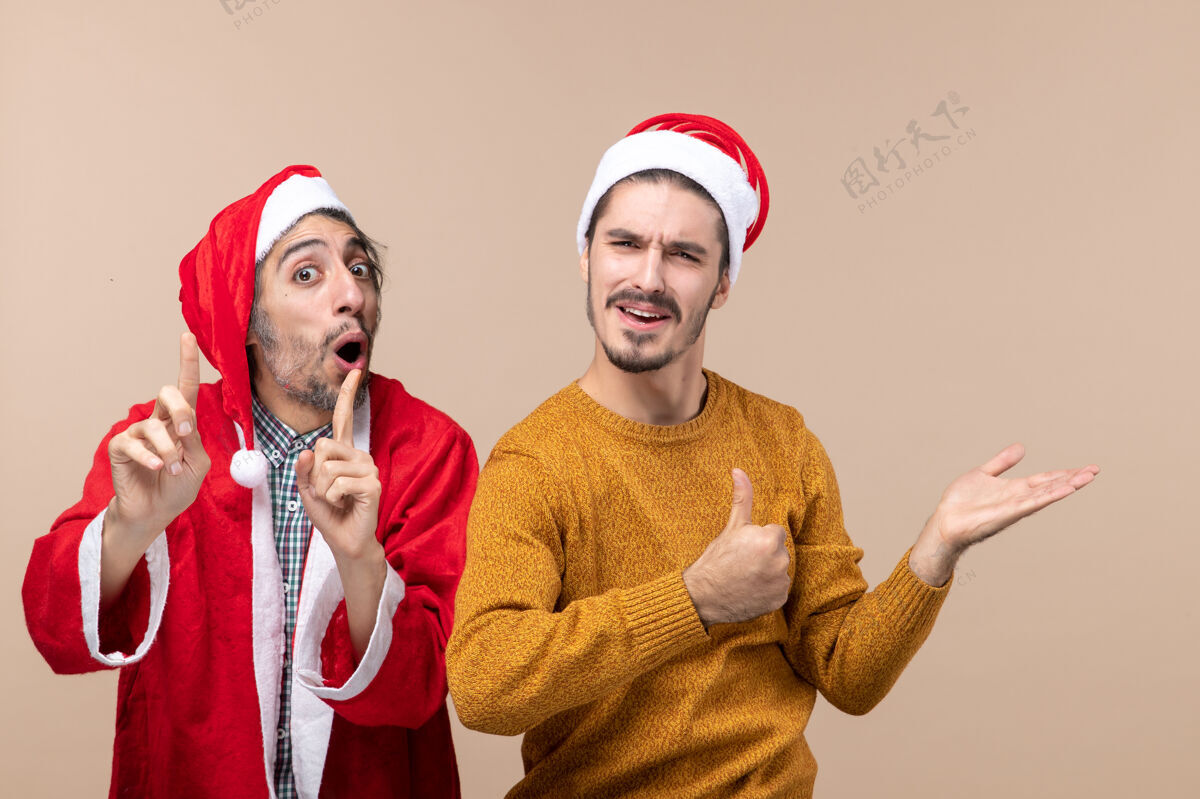 男人前视图两个男人一个手指放在嘴上 另一个在米色孤立的背景上展示东西两个两个男人视图