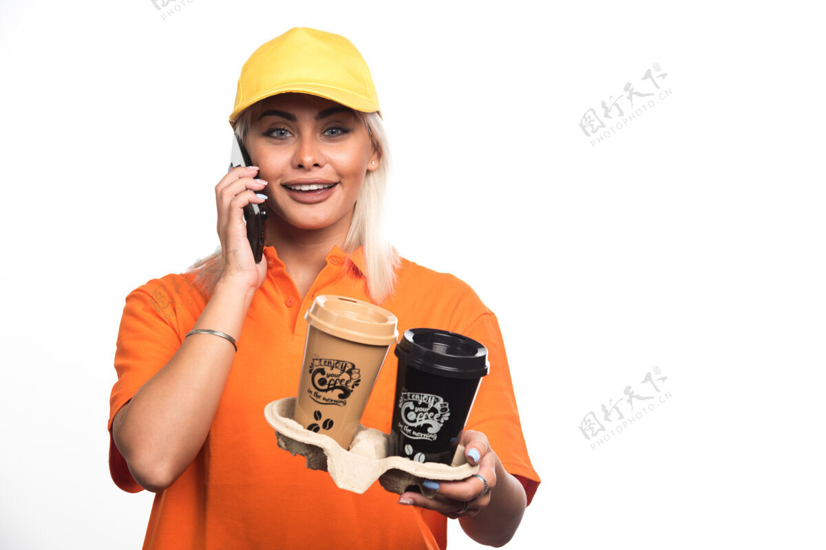 女性女信使拿着两杯白底咖啡一边打电话高质量的照片塑料咖啡外卖