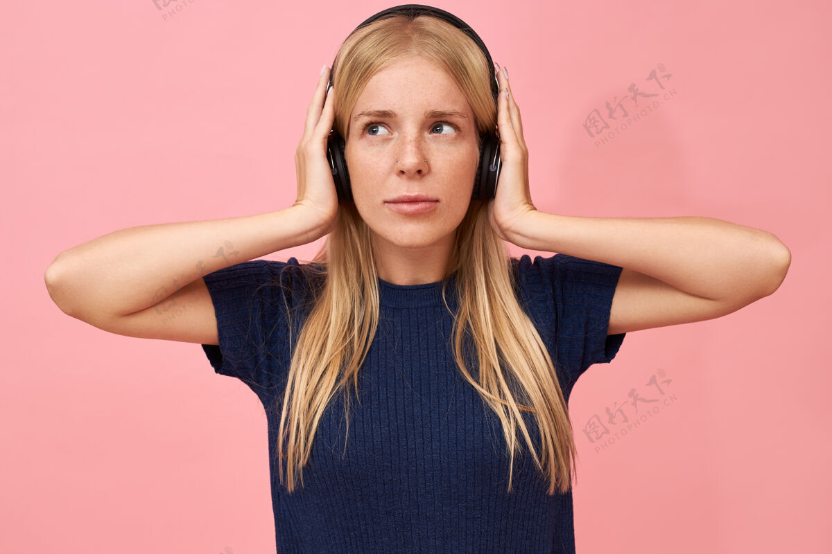时尚一个可爱的少女手放在耳朵上 用无线耳机在mp3播放器中欣赏高品质音乐的孤立镜头女人放松耳机