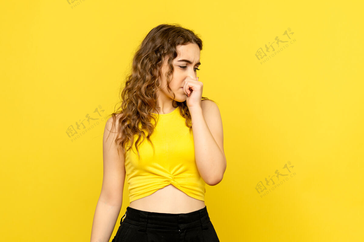 女士年轻女子在黄色墙壁上闭上鼻子的前视图情感鼻子模特