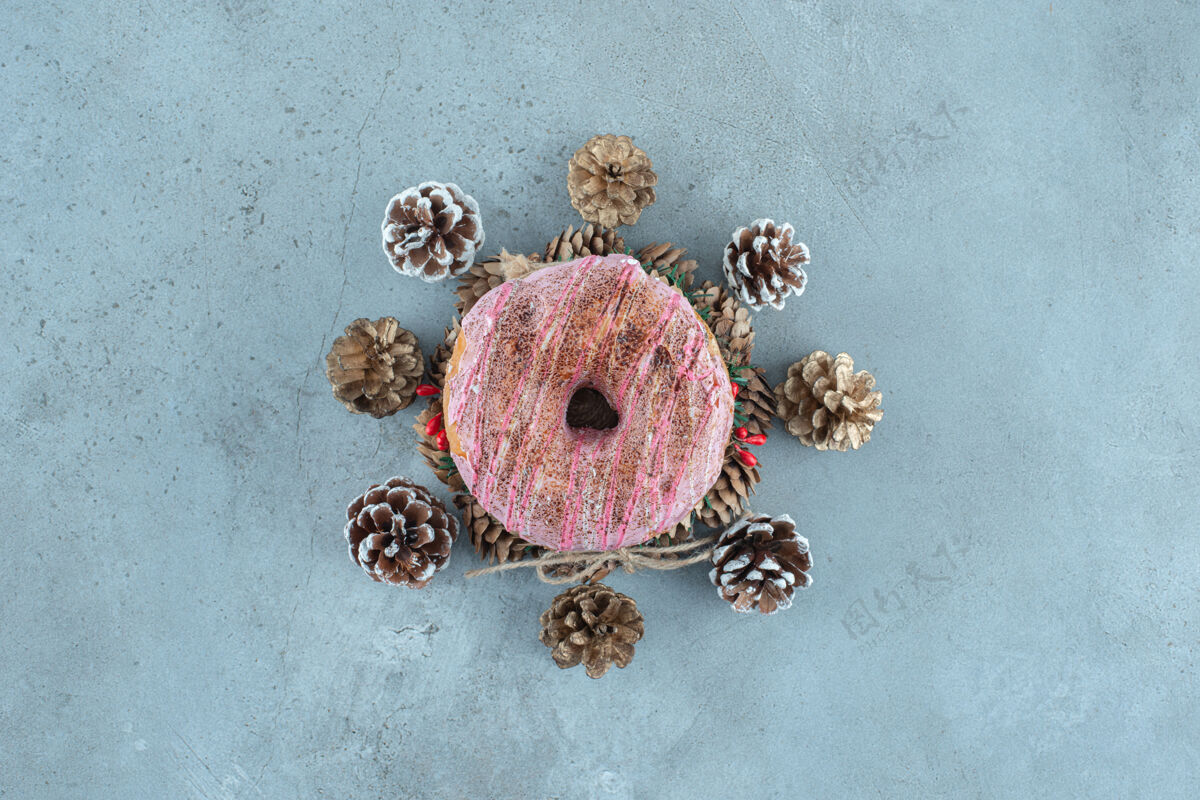 甜点在大理石表面的花环上 松果围绕着一个甜甜圈甜味美味装饰性