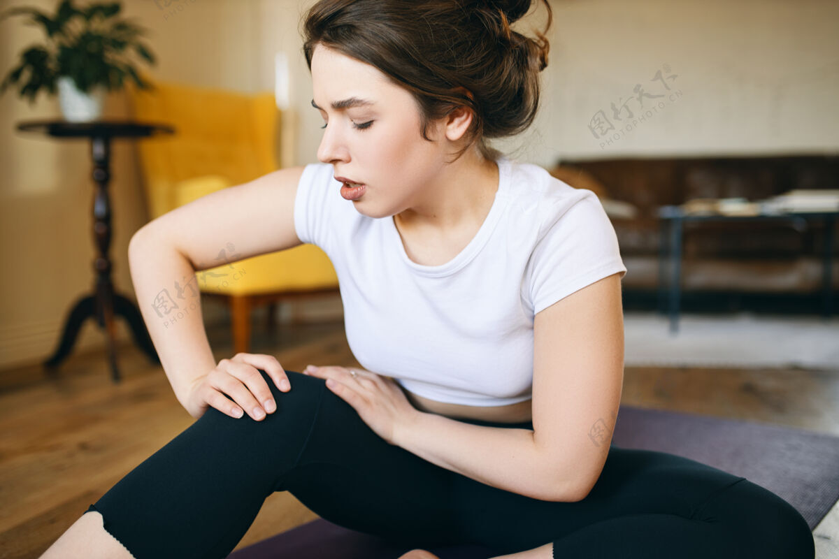受伤不开心的运动女孩抓起膝盖 试图按摩疼痛部位 因为运动受伤无法做瑜伽 感觉疼痛女性紧张脚