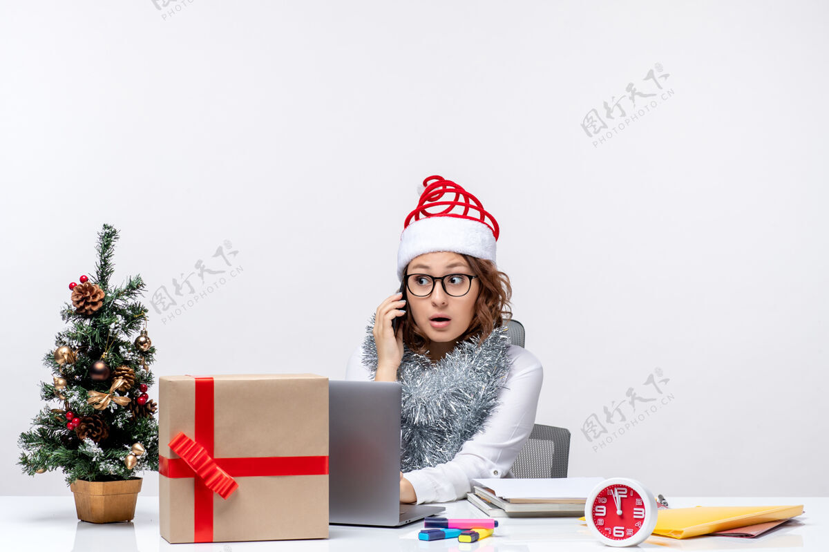 正面前视图年轻女性在假日工作时使用白色背景的笔记本电脑圣诞节年轻办公室
