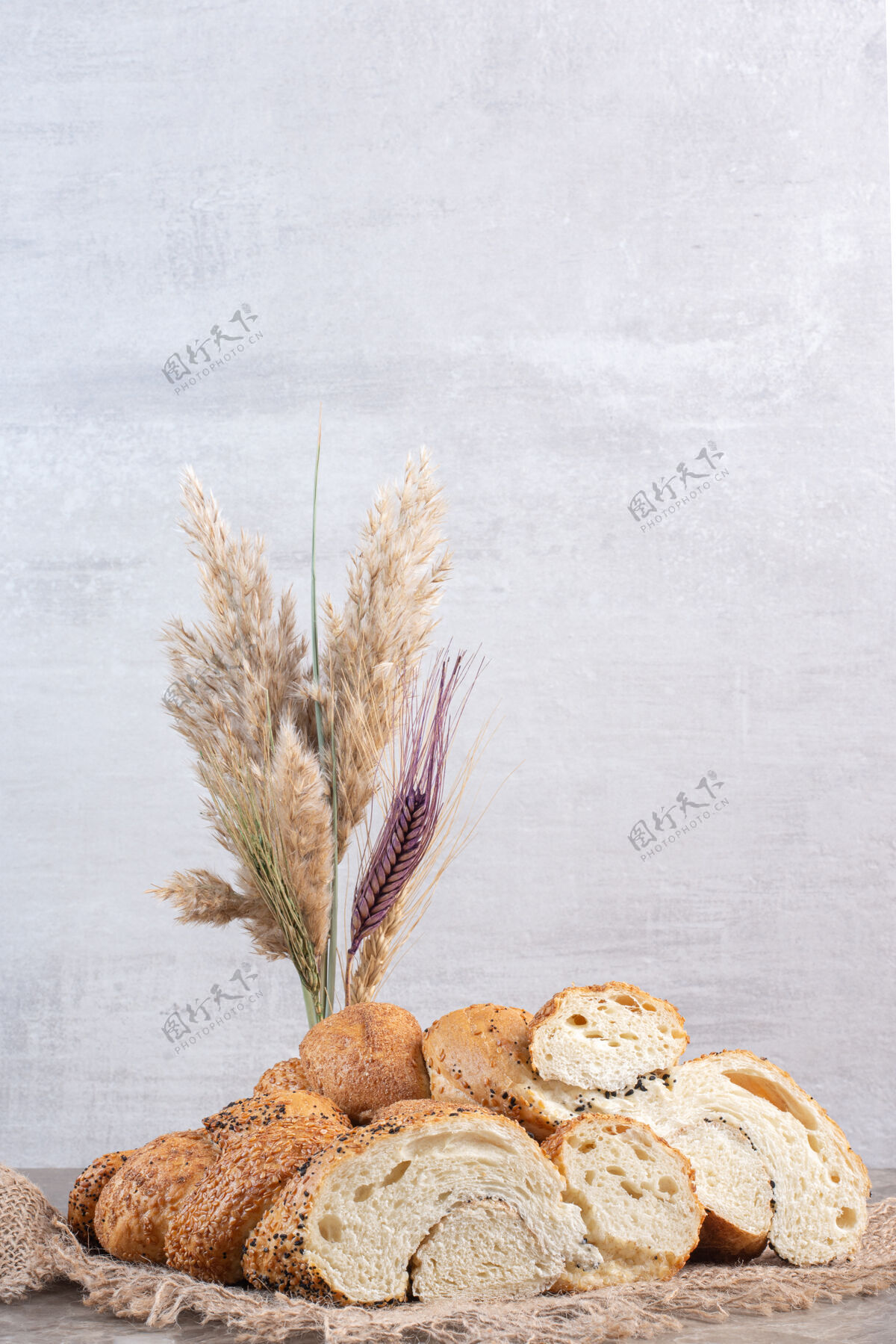 烘焙食品一捆裹着芝麻的切片面包 麦秆放在大理石上面团涂料小麦