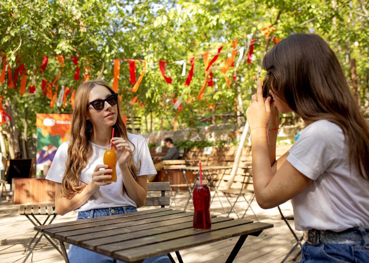 饮食中镜头的朋友拿着新鲜的果汁瓶拍照异国情调水果食品果汁