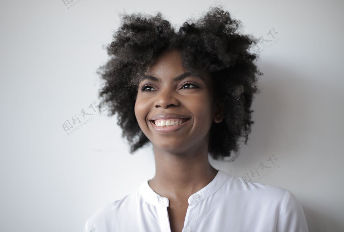 美国人美丽的非洲裔美国女性站在白色的墙上 面带微笑表情风格孤独