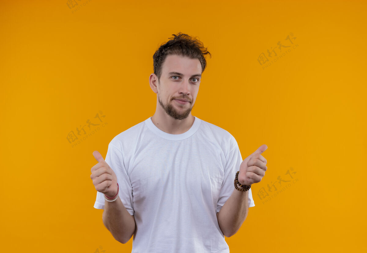 小伙子穿着白色t恤的年轻人很高兴 他在孤立的橙色背景上竖起大拇指白色向上拇指