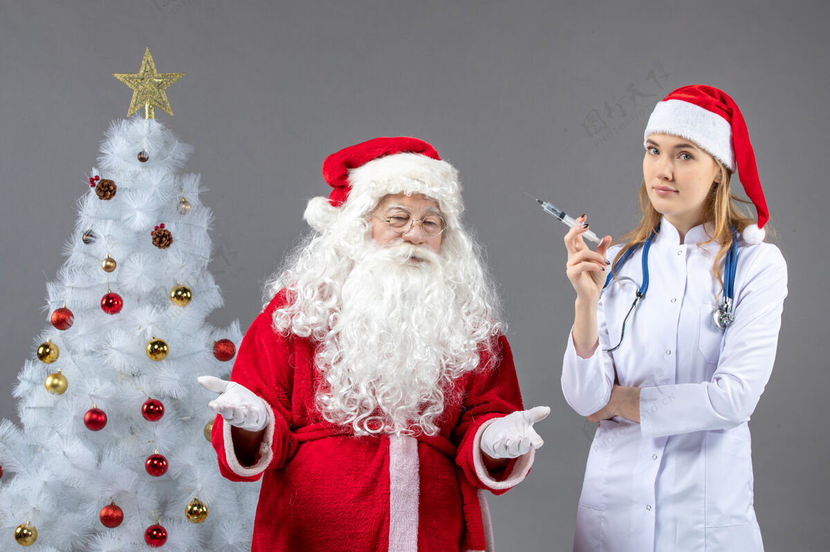 圣诞老人圣诞老人和女医生在灰色墙上打针的前视图前面医生十二月