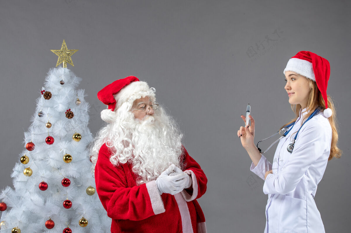 前面圣诞老人和女医生在灰色墙上打针的前视图肖像人们男性