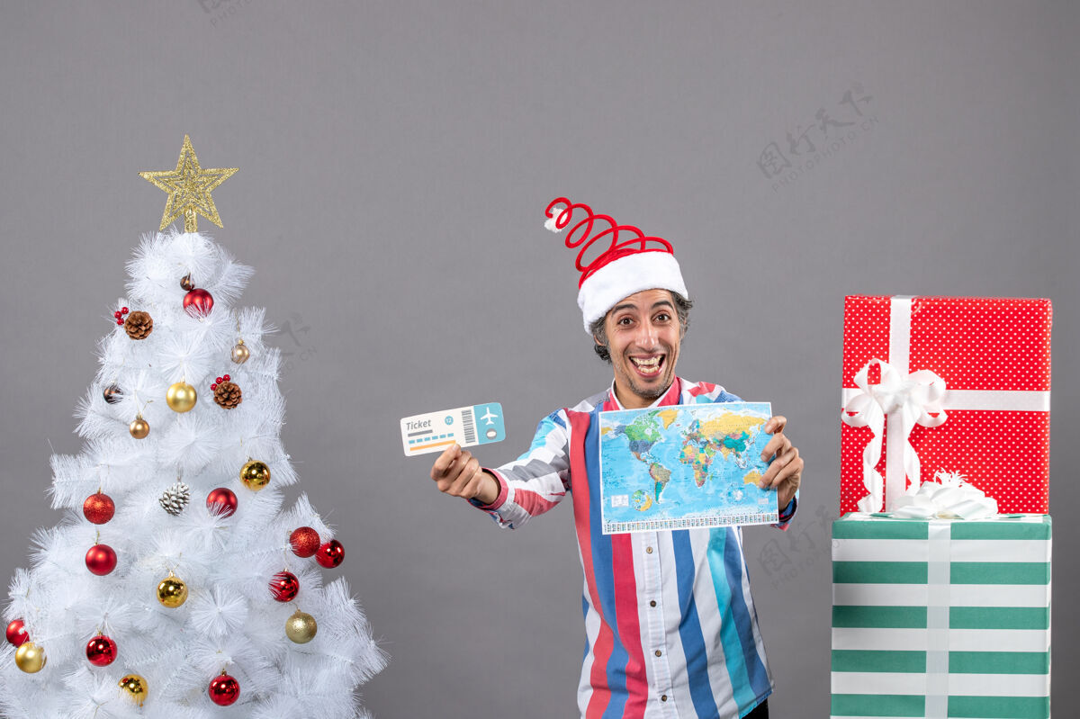 人前视图快乐的人拿着世界地图和旅行票站在圣诞树旁 有复印空间帽子票假期