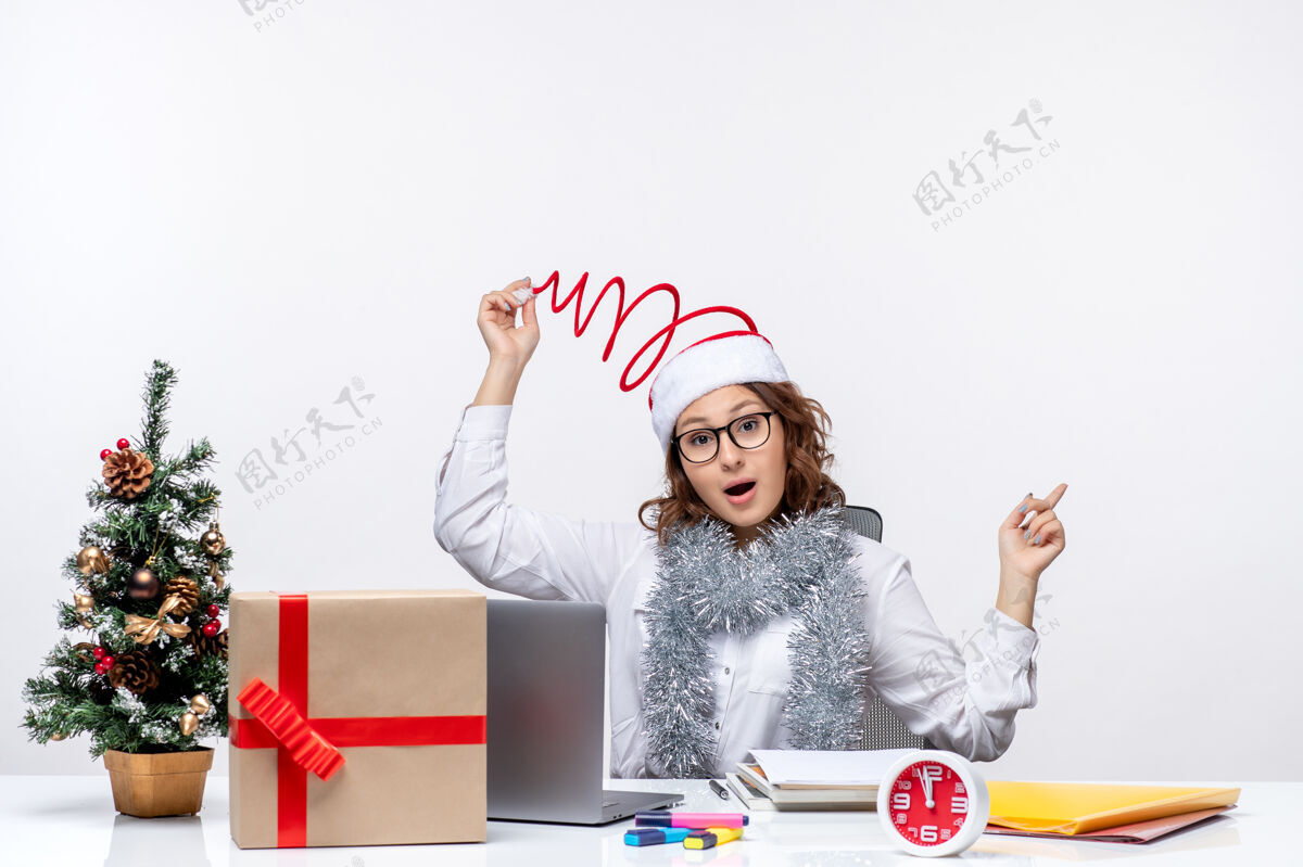 前面正面图：年轻的女工坐在白色背景的工作场所前艺术工作圣诞节