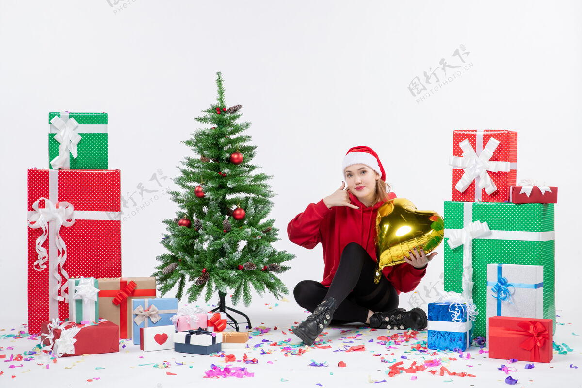 礼物正面图：年轻女子围坐在白色墙壁上 手持金心形礼物举行礼物圣诞