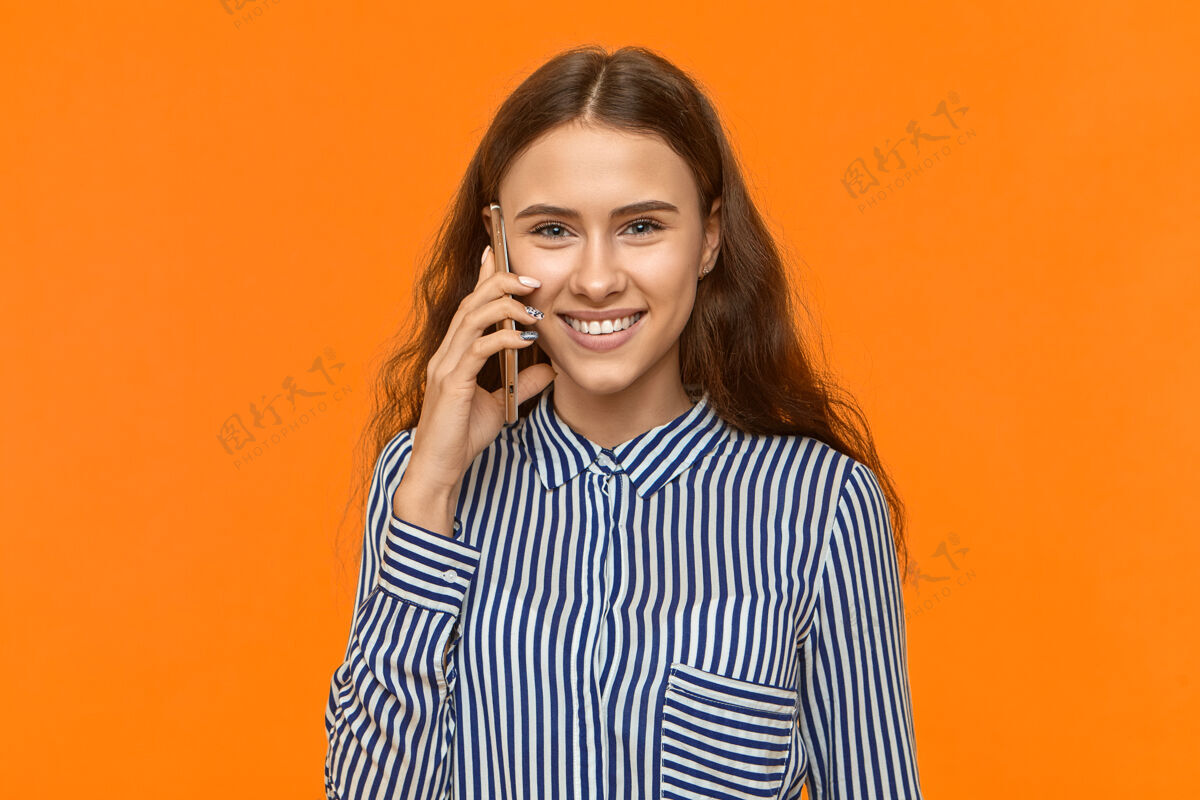 成人可爱的年轻女性把手机放在耳边 开心地笑着 和男朋友说话通话智能手机交谈