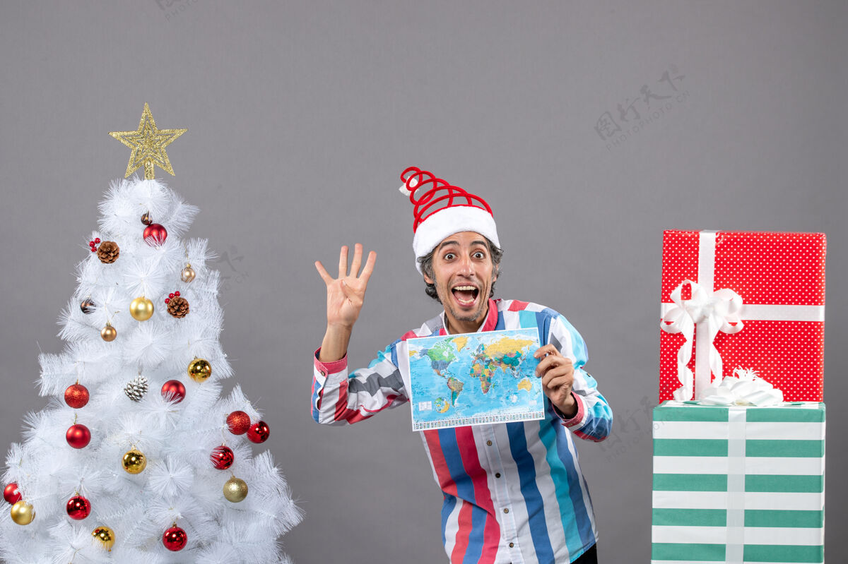 人们正面图：戴着螺旋弹簧圣诞帽的快乐男人向上伸出四个手指圣诞老人显示男人