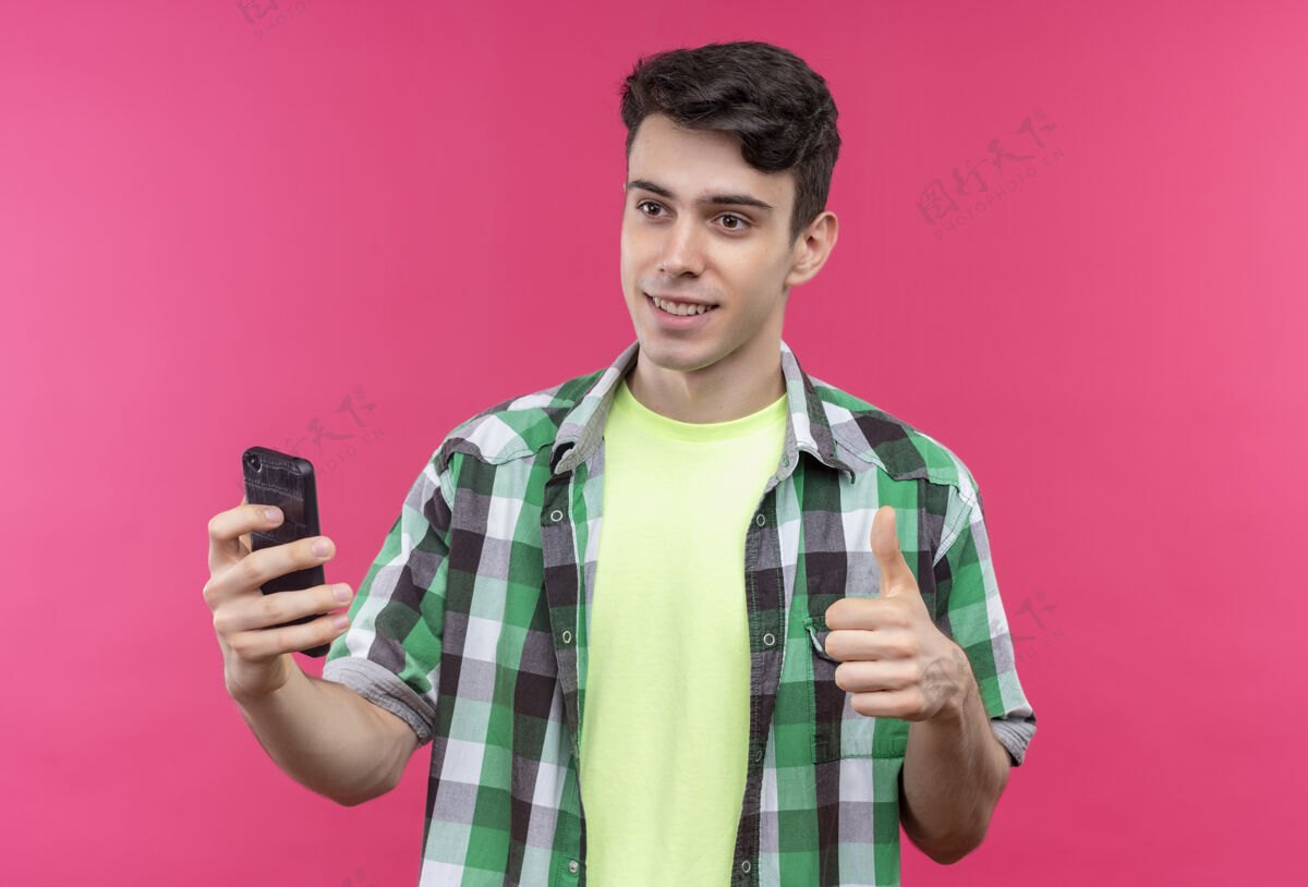 向上微笑的白人年轻人穿着绿色衬衫 在孤立的粉色背景上举着大拇指粉色绿色小伙子