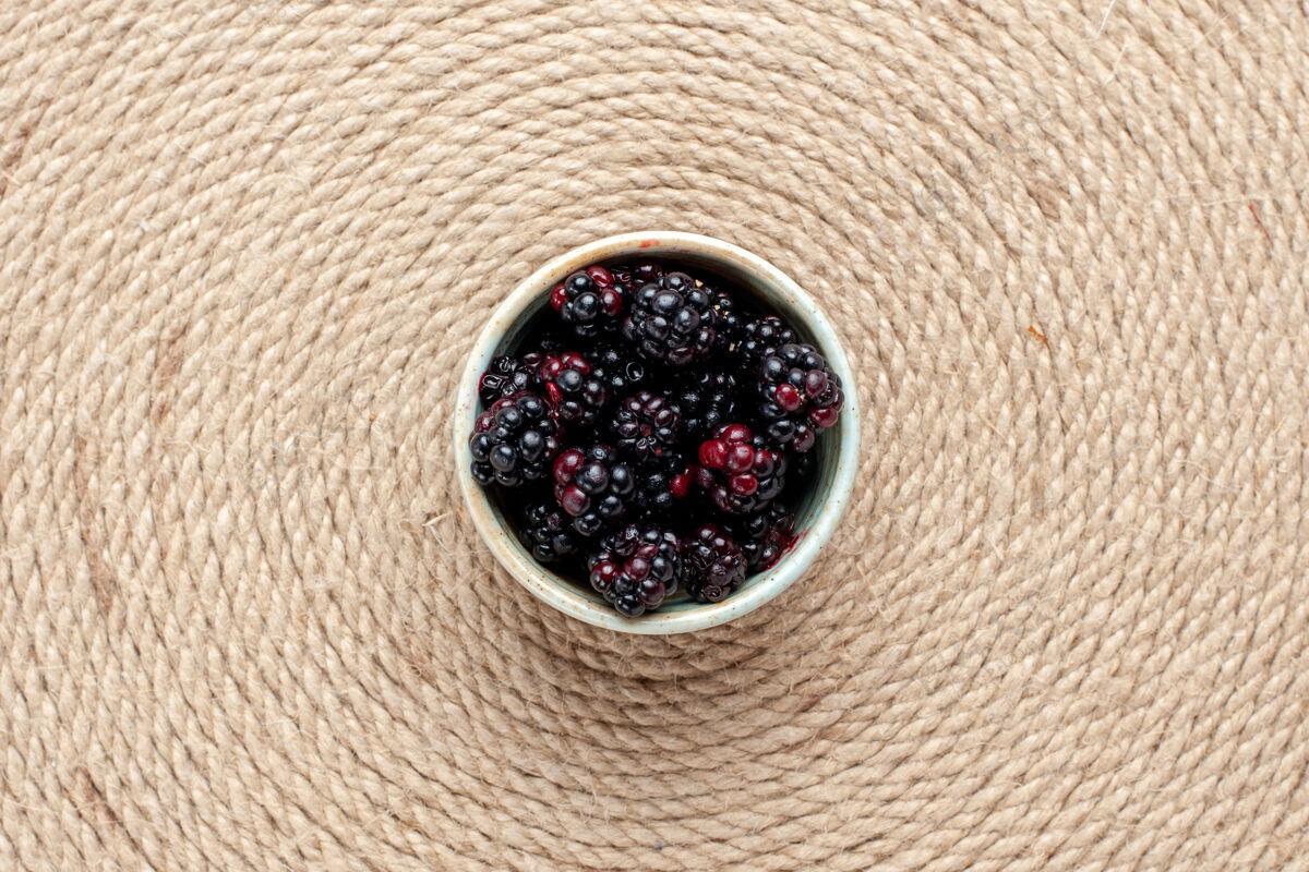接近在粉红色书桌上的白色小锅里俯瞰新鲜的黑莓新鲜小水果