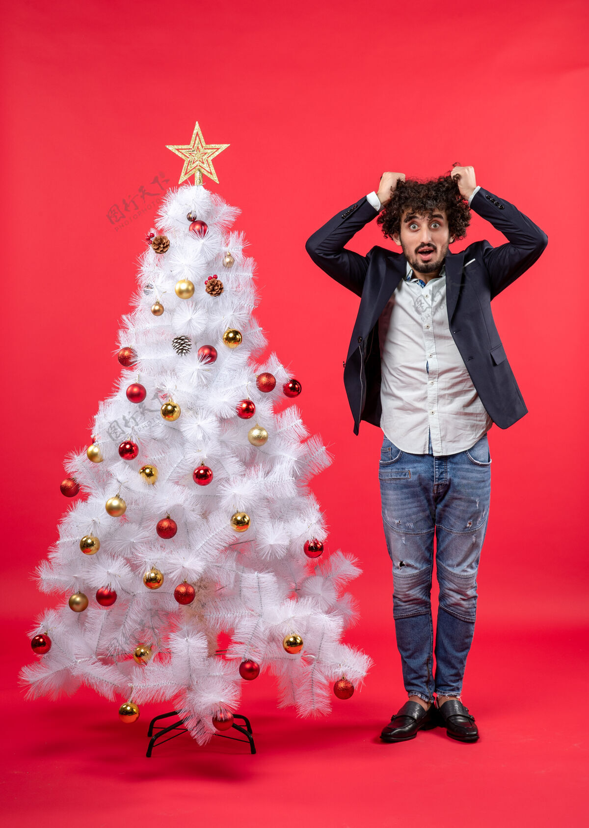 一切圣诞庆典上 满脸胡须的年轻人精疲力尽 站在圣诞树旁感到极度紧张男人快乐非常